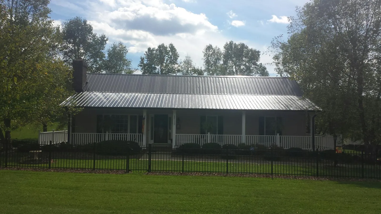 Gray metal roof on a brick ranch with a full width front porch — Gutter Guard Installation work by our crew in Dakota City