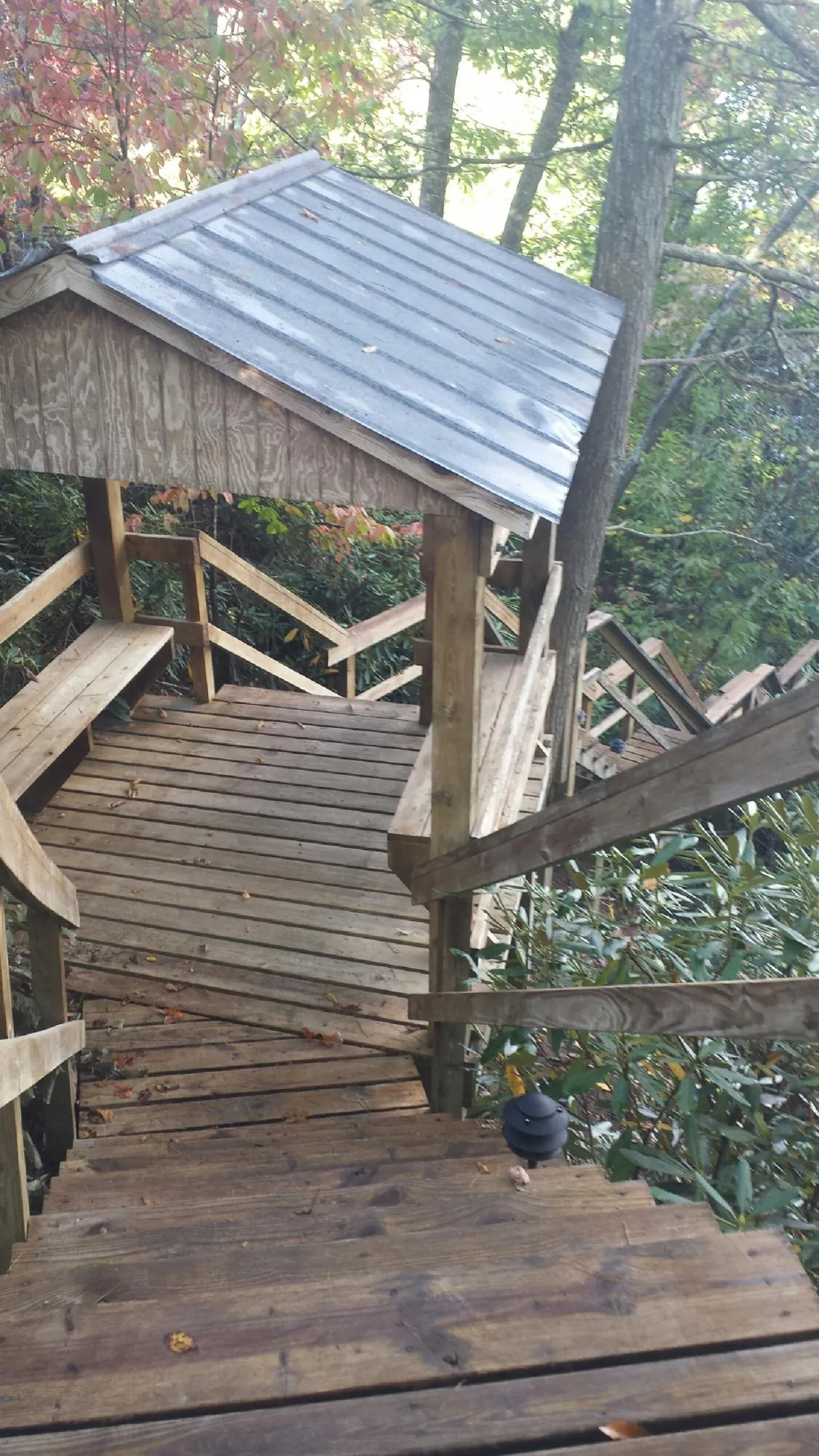 Metal roofed shelter over wooden steps on a wooded walkway — Skylight Repair & Installation work by our crew in Dakota City